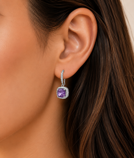Close-up of an ear wearing a purple gemstone earring with a neutral background