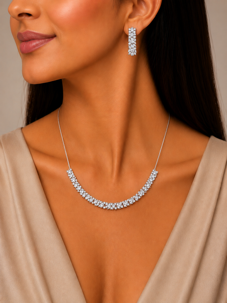 Woman wearing a silver necklace and earrings against a neutral background