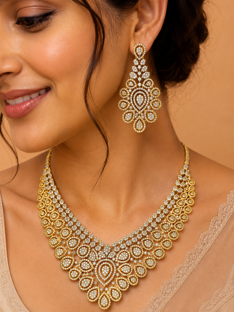 Woman wearing a gold necklace and earrings with a neutral background