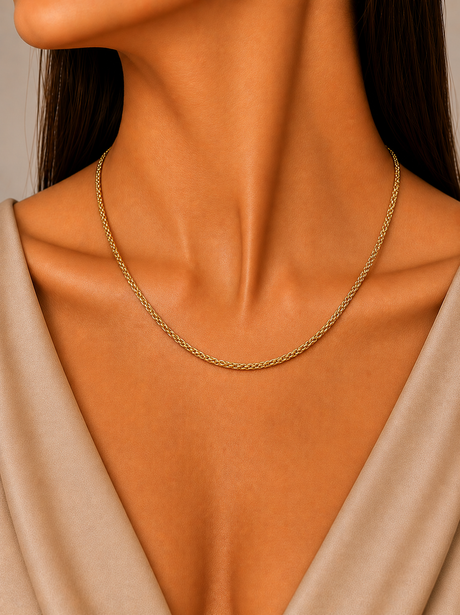 Gold necklace on a person wearing a beige top