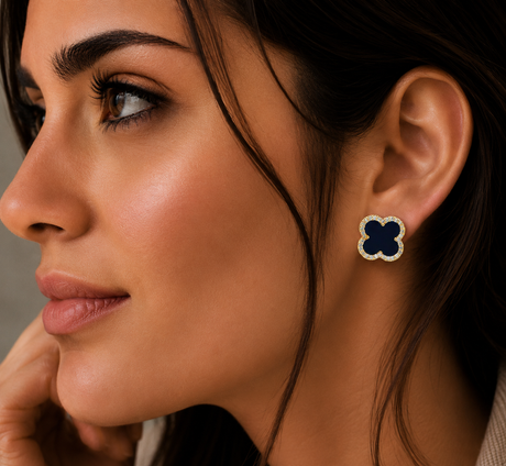 Close-up of a woman wearing a clover-shaped earring with a dark blue center and gold accents.