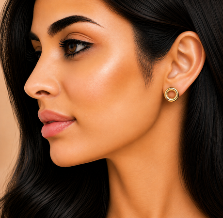 Close-up of a woman wearing gold hoop earrings with a neutral background
