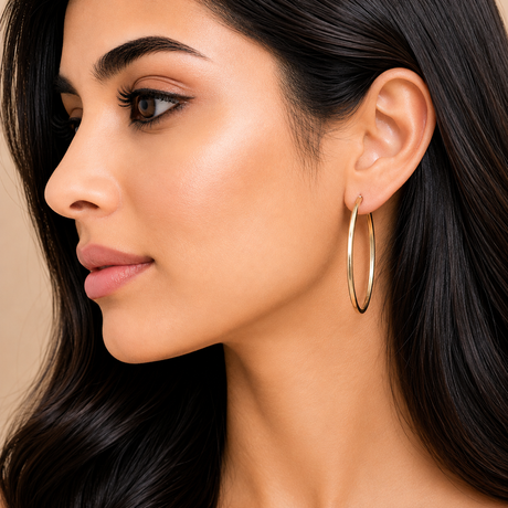 Close-up of a woman wearing gold hoop earrings with a neutral background