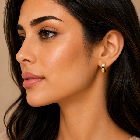 Close-up of a woman wearing a gold hoop earring against a neutral background