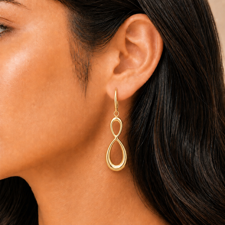 Gold earrings worn by a person with dark hair.