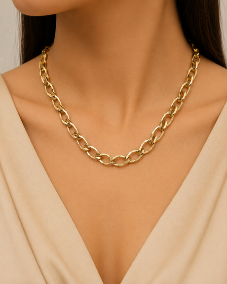 Gold chain necklace worn by a model against a neutral background