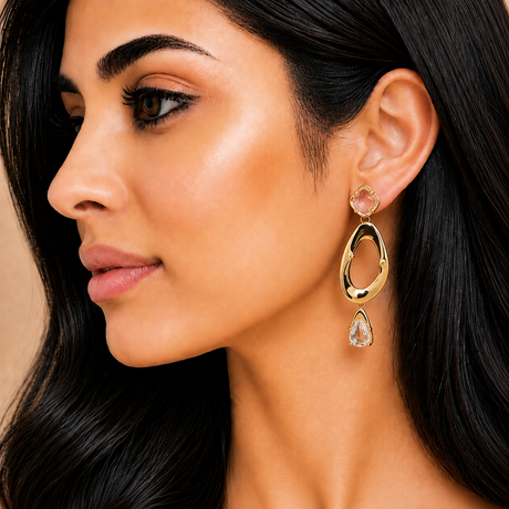 Close-up of a woman wearing gold earrings with gemstones.