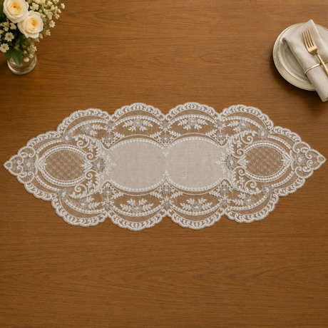 Lace table runner on a wooden table with a floral arrangement and plates in the background.