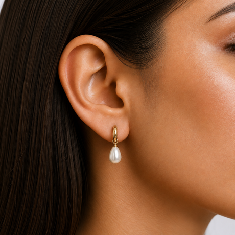 Pearl earring worn by a person with dark hair and a neutral background
