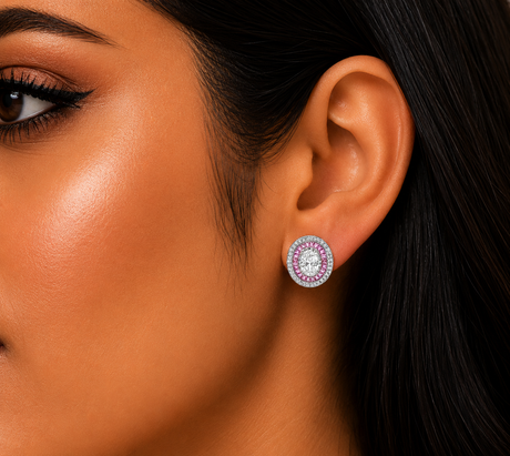 Close-up of a woman's ear wearing a silver earring with pink gemstones.