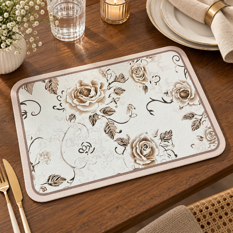 A rectangular table mat with a beige and brown rose pattern, displayed on a wooden dining table alongside a gold knife, glass, and plates.