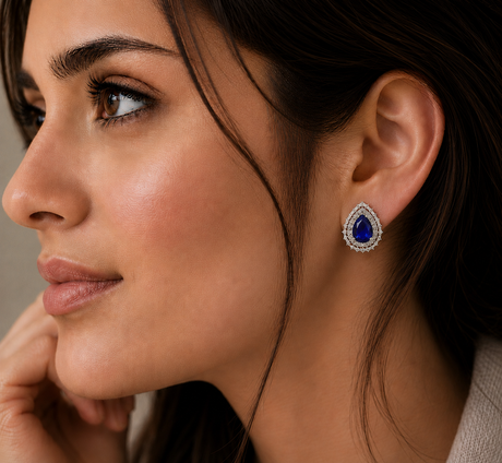 Close-up of a woman wearing a blue gemstone earring with a neutral background