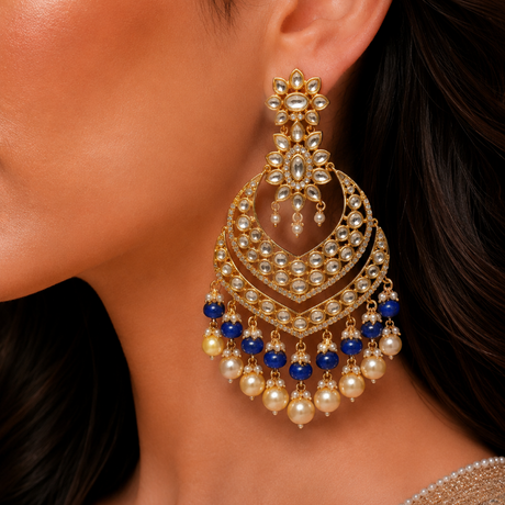 Close-up of a woman wearing a pair of gold, blue, and pearl earrings.