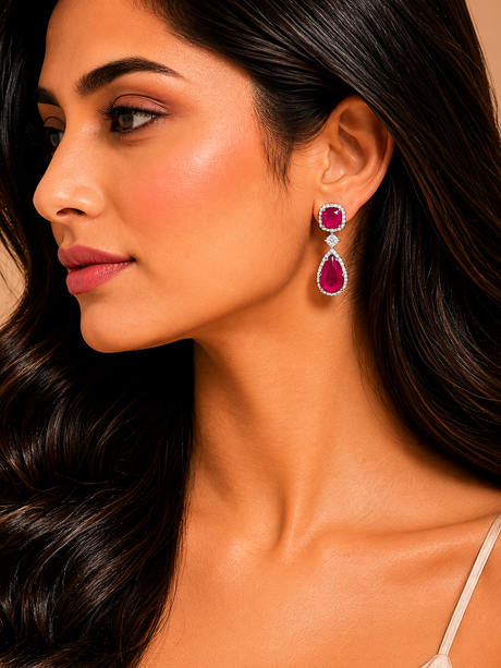 Close-up of a woman wearing red teardrop earrings with a neutral background