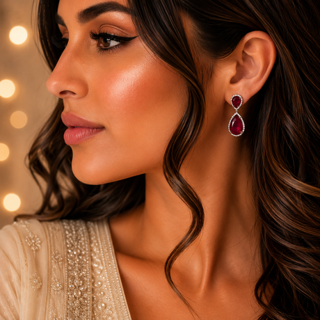 Close-up of a woman wearing red teardrop earrings with a blurred lights background