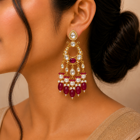 Close-up of a woman wearing a gold earring with red and white gemstones.