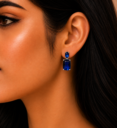 Close-up of a woman wearing blue gemstone earrings with a blurred background
