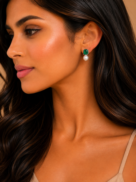 Close-up of a woman wearing emerald and pearl earrings.