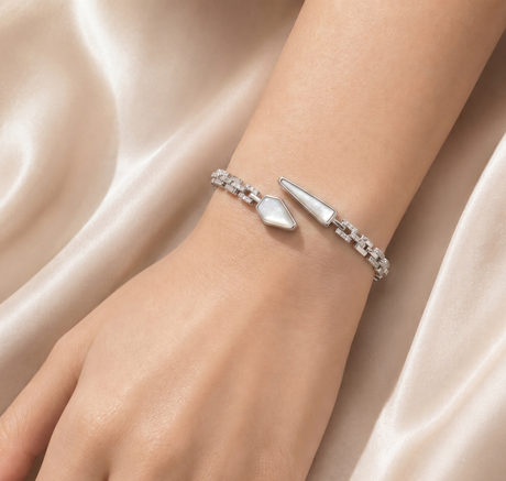 Silver bracelet with a unique design on a wrist against a soft fabric background