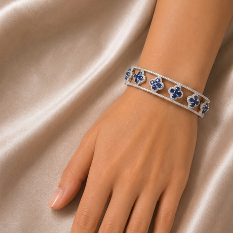 Silver bracelet with blue stones on a hand against a satin background