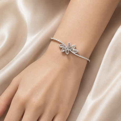 Silver bracelet with floral design on a wrist against a soft pink fabric background