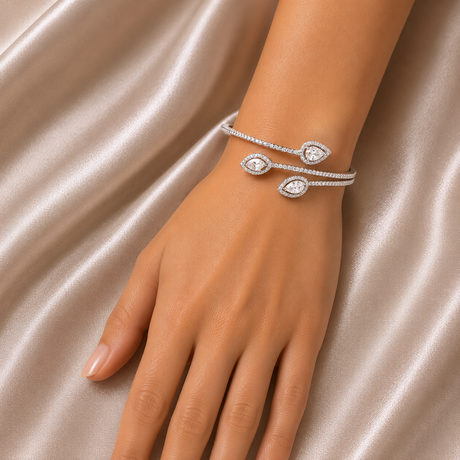Silver bracelet with heart-shaped charms on a hand against a satin background