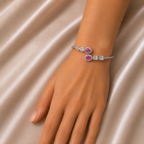 Silver bracelet with pink gemstones on a hand against a beige fabric background