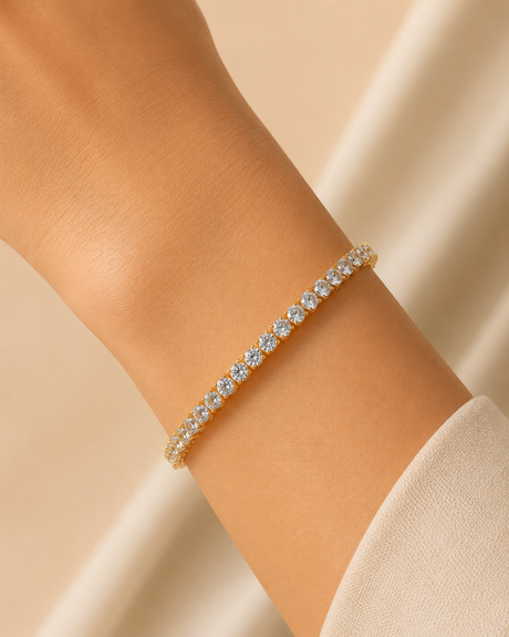 Gold bracelet with clear stones on a wrist against a beige background