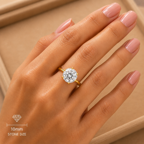 Gold ring with a diamond on a hand against a beige background