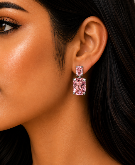 Close-up of a woman wearing pink square earrings with dark hair and black background