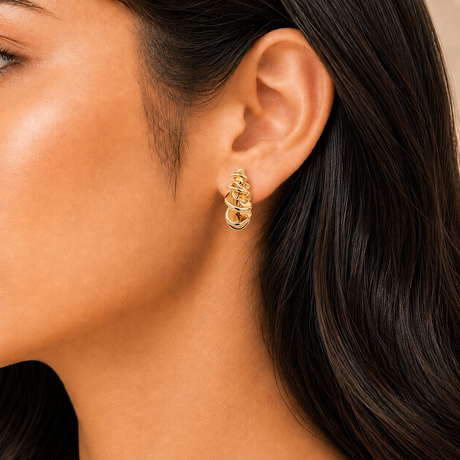 Close-up of a person wearing a gold hoop earring with dark hair.