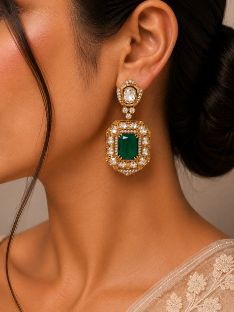 Close-up of a woman wearing a gold earring with a green gemstone.