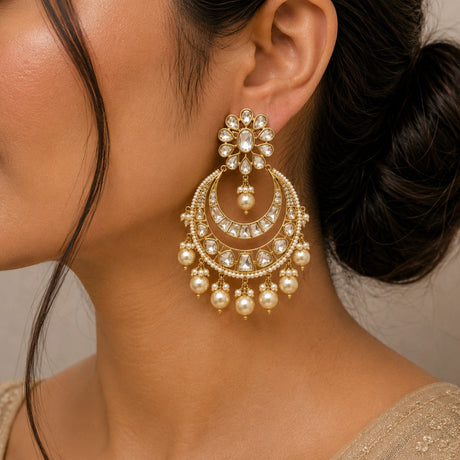 Close-up of a woman wearing a gold and pearl earring with a neutral background