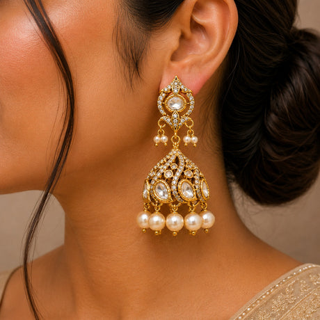Close-up of a woman wearing gold and pearl earrings with a neutral background