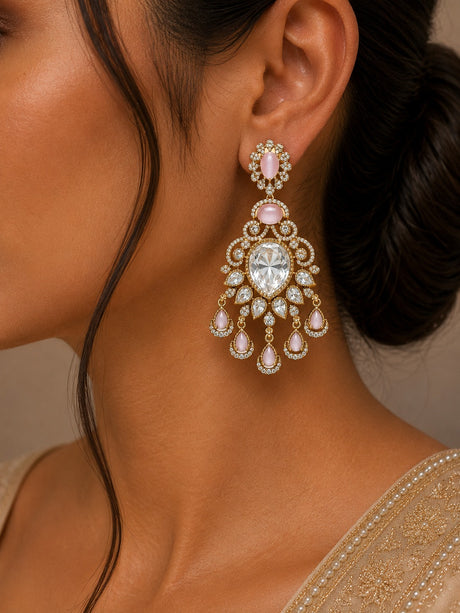 Close-up of a woman wearing a pair of ornate earrings with pink gemstones.