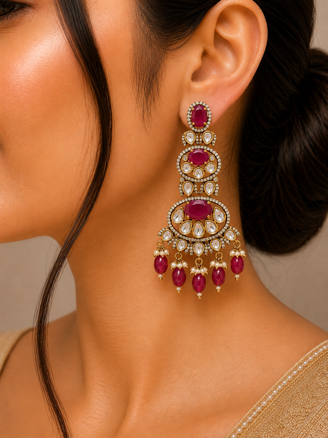 Close-up of a woman wearing a pair of ornate earrings with red gemstones.