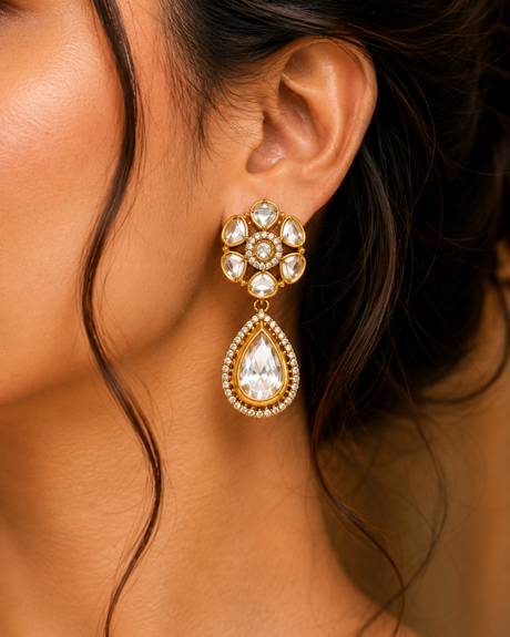 Close-up of a woman wearing a gold and crystal earring.