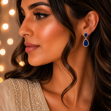 Close-up of a woman wearing blue teardrop earrings with a blurred background