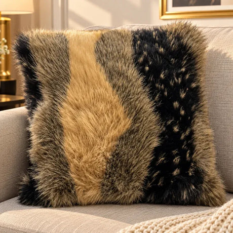Brown faux fur cushion cover with camel and black bands on a beige sofa with a cream knit throw