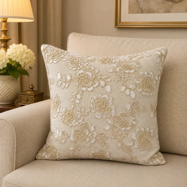 Ivory rose embroidered cushion cover styled on a cream armchair beside a table lamp