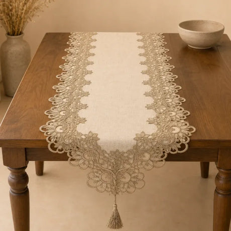 Decorative lace table runner on a wooden table with a vase and bowl in the background.