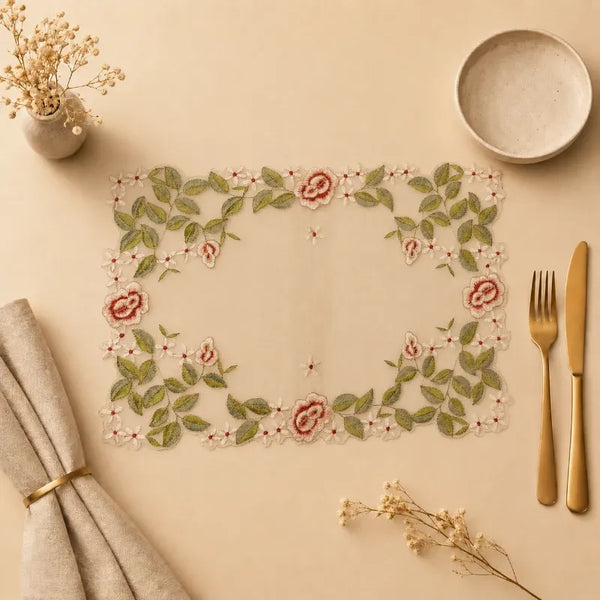 Decorative placemat with floral design on a beige surface with cutlery and napkins.