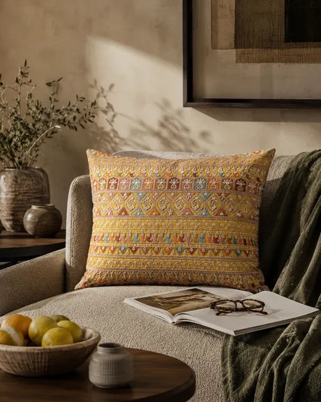 Traditional embroidered cushion cover styled on a beige living room armchair