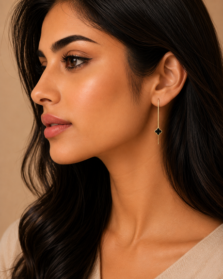 Close-up of a woman wearing a dangling earring with a black gemstone on a beige background